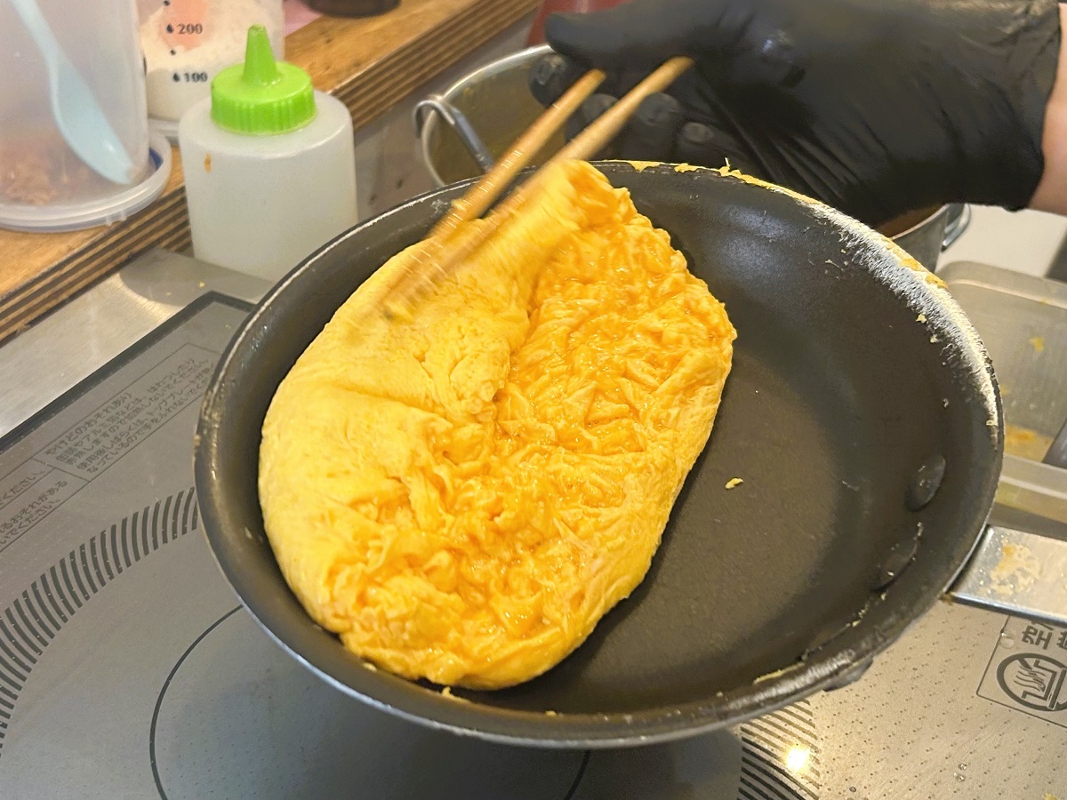 ▲高速でかき混ぜながらとろとろの卵をまとめあげる、流れるような手捌きはまるで芸術